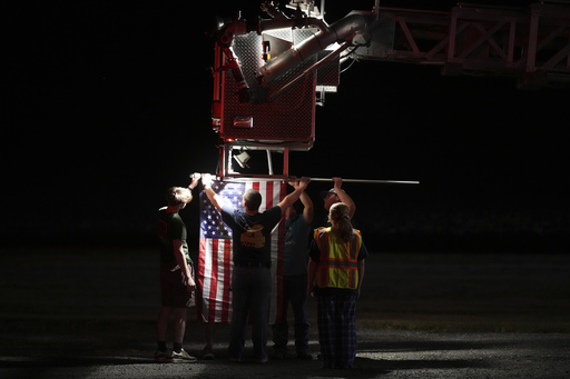Firefighters attach an American flag to a firetruck before a procession after multiple police officers were shot and killed Wednesday, Sept. 17, 2025, in Spring Grove, Pa. (AP Photo/Matt Slocum)