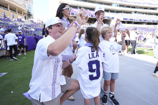 Blake Bonner, left, his wife Caitlin, left rear, standing and their daughter, front, wearing a shirt with her late sisters name stand in the end zone before an NCAA college football game between SMU and TCU, Saturday, Sept. 20, 2025, in Fort Worth, Texas. (AP Photo/Tony Gutierrez)