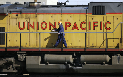 FILE - A maintenance worker walks past the company logo on the side of a locomotive in the Union Pacific Railroad fueling yard in north Denver, Oct. 18, 2006. (AP Photo/David Zalubowski, File)