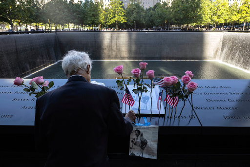 FILE - Hagi Abucar places flowers for his former coworker Lindsey Herkness on the south reflecting pool during the 9/11 Memorial ceremony on the 23rd anniversary of the Sept. 11, 2001 attacks, Sept. 11, 2024, in New York. (AP Photo/Yuki Iwamura, File)