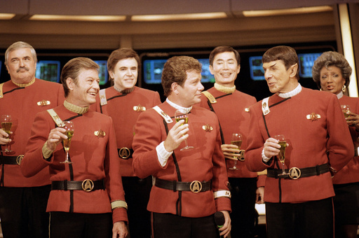 FILE- Members of the "Star Trek" crew, from left, James Doohan, DeForest Kelley, Walter Koenig, William Shatner, George Takei, Leonard Nimoy, and Nichelle Nichols, toast the newest "Star Trek" film at Paramount Studios on Dec. 28, 1988. (AP Photo/Bob Galbraith, File)