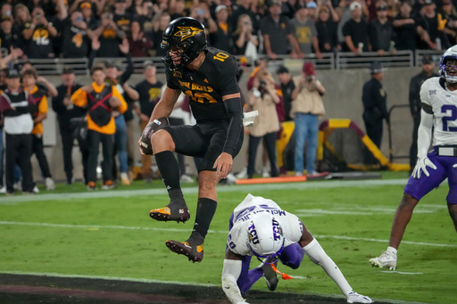 Arizona State Sun Devils quarterback Sam Leavitt (10) scores a touchdown as he jumps over TCU Horned Frogs cornerback Jevon McIver Jr. (20) during the first half of an NCAA college football game Friday, Sept. 26, 2025, in Tempe, Ariz. (AP Photo/Darryl Webb)