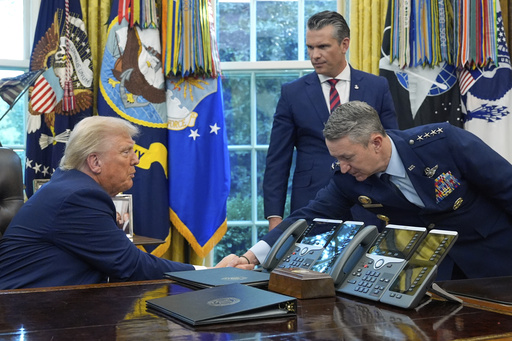 President Donald Trump shakes hands with Chairman of the Joint Chiefs of Staff Gen. Dan Caine as Defense Secretary Pete Hegseth watches in the Oval Office of the White House, Friday, Sept. 5, 2025, in Washington. (AP Photo/Alex Brandon)