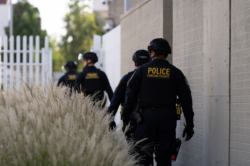 Department of Homeland Security officials walk to the gates of the U.S. Immigration and Customs Enforcement facility after inspecting an area outside on Sunday, Sept. 28, 2025, in Portland, Ore. (AP Photo/Jenny Kane)