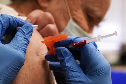 FILE - Pharmacist Kenni Clark injects Robert Champion, of Lawrence, Mass., with a booster dosage of the Moderna COVID-19 vaccine during a vaccination clinic at City of Lawrence's "The Center," Dec. 29, 2021, in Lawrence, Mass. (AP Photo/Charles Krupa, File)