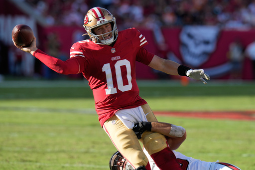 San Francisco 49ers quarterback Mac Jones (10) passes the ball over Tampa Bay Buccaneers linebacker Anthony Nelson, bottom, during the first half of an NFL football game in Tampa, Fla., Sunday, Oct. 12, 2025. (AP Photo/Chris O'Meara)