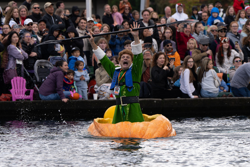 Gary Kristensen, dressed up as the character Buddy from the holiday movie "Elf," celebrates after winning a race during the West Coast Giant Pumpkin Regatta on Sunday, Oct. 19, 2025, in Tualatin, Ore. (AP Photo/Jenny Kane)