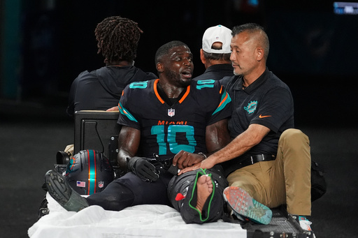 Miami Dolphins wide receiver Tyreek Hill (10) talks with a staff member as he is carted off the field after suffering an unknown lower leg injury in the second half of an NFL football game against the New York Jets, Monday, Sept. 29, 2025, in Miami Gardens, Fla. (AP Photo/Rebecca Blackwell)