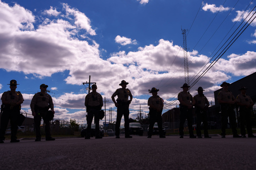 Illinois State Police stand guard as people including members of the Coalition for Spiritual and Public Leadership (CSPL) gather outside a U.S. Immigration and Customs Enforcement facility in Broadview, Ill., Saturday, Oct. 11, 2025. (AP Photo/Adam Gray)