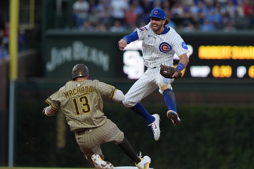 Chicago Cubs' Dansby Swanson leaps over San Diego Padres' Manny Machado to make a play on a ball hit by Jackson Merrill during the sixth inning of Game 3 of a National League wild card baseball game Thursday, Oct. 2, 2025, in Chicago. (AP Photo/Nam Huh)