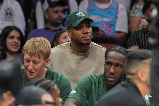 Milwaukee Bucks forward Giannis Antetokounmpo, who is recovering from COVID-19, sits behind his team's bench as he watches the second half of a preseason NBA basketball game against the Miami Heat, Monday, Oct. 6, 2025, in Miami. (AP Photo/Rebecca Blackwell)