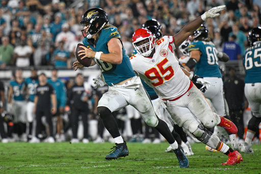 Jacksonville Jaguars quarterback Trevor Lawrence (16) gets past Kansas City Chiefs defensive tackle Chris Jones (95) as he runs the ball during the second half of an NFL football game, Monday, Oct. 6, 2025, in Jacksonville, Fla. (AP Photo/Phelan M. Ebenhack)