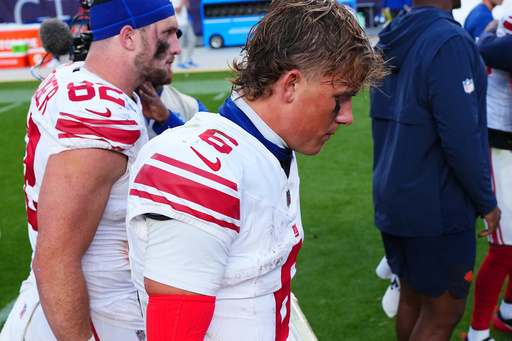 New York Giants tight end Daniel Bellinger, left, and quarterback Jaxson Dart walk off the field after an NFL football game against the Denver Broncos in Denver, Sunday, Oct. 19, 2025. (AP Photo/Jack Dempsey)