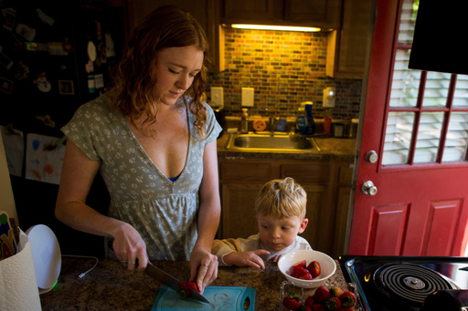 Taylor Moyer slices strawberries as her youngest son, Bradley, helps put the sliced fruit into a bowl while at home in the kitchen, Sunday, Oct. 5, 2025, in Virginia Beach, Va. (AP Photo/John Clark)