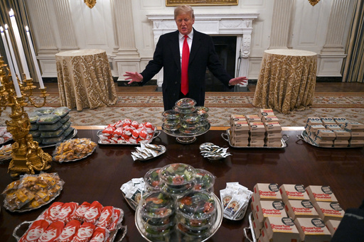 FILE - President Donald Trump talks to reporters about the table full of fast food in the State Dining Room of the White House in Washington, Jan. 14, 2019, for the reception for the Clemson Tigers. (AP Photo/Susan Walsh)