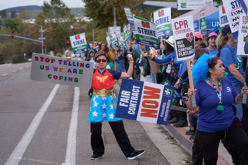 Kaiser Permanente health care workers hold signs and chant slogans while on strike in front of the Kaiser Permanente San Diego Medical Center Tuesday, Oct. 14, 2025, in San Diego. (AP Photo/Gregory Bull)