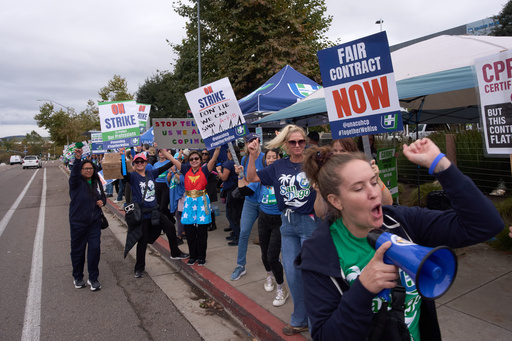 Kaiser Permanente health care workers hold signs and chant slogans while on strike in front of the Kaiser Permanente San Diego Medical Center Tuesday, Oct. 14, 2025, in San Diego. (AP Photo/Gregory Bull)