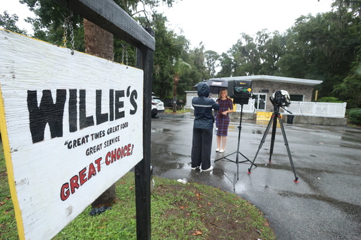 A reporter works outside of Willie's Bar and Grill in St Helena Island, S.C. after a shooting occurred early Sunday, Oct. 12, 2025. (AP Photo/Lewis M. Levine)