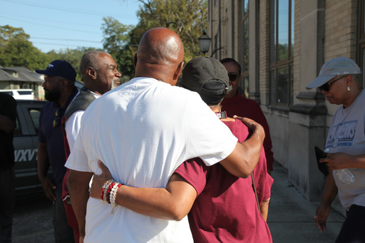 Friends and family of victims of a homecoming shooting embrace in downtown Leland, Miss., Saturday, Oct. 11, 2025. (AP Photo/Katie Adkins)