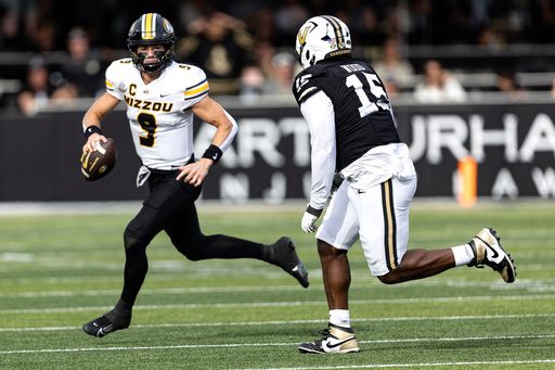 Missouri quarterback Beau Pribula (9) looks for a receiver as he's chased by Vanderbilt defensive lineman Zaylin Wood (15) during the first half of an NCAA college football game, Saturday, Oct. 25, 2025, in Nashville, Tenn. (AP Photo/Wade Payne)