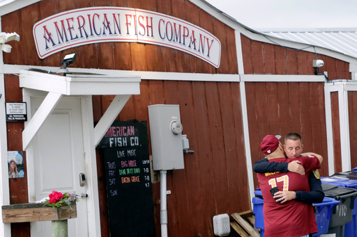 A man hugs a police officer in front of the American Fish Company following a fatal shooting that occurred the night before, Sunday, Sept. 28, 2025, in Southport, N.C. (AP Photo/Chris Seward)