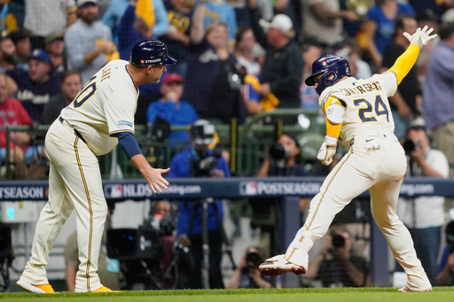 Milwaukee Brewers' William Contreras (24) celebrates with third base coach Jason Lane (40) after hitting a solo home run during the third inning of Game 2 of baseball's National League Division Series against the Chicago Cubs Monday, Oct. 6, 2025, in Milwaukee. (AP Photo/Kayla Wolf)