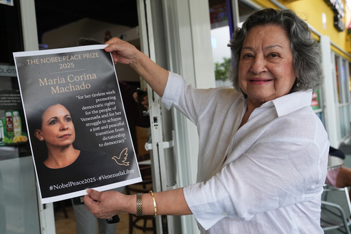 Iris Wilthew holds a poster in support of Venezuelan opposition leader Maria Corina Machado winning the Nobel Peace Prize, Friday, Oct. 10, 2025, in Doral, Fla. (AP Photo/Lynne Sladky)