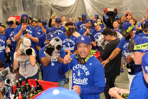 Los Angeles Dodgers manager Dave Roberts celebrates in the clubhouse with his team after a win over the Cincinnati Reds in Game 2 of the National League Wild Card baseball playoff series Wednesday, Oct. 1, 2025, in Los Angeles. (AP Photo/Mark J. Terrill)