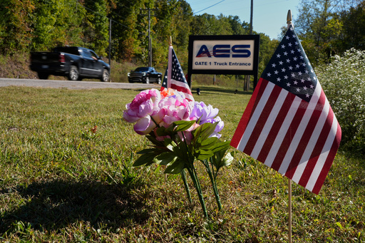 Flowers and flags rest at the entrance to Accurate Energetic Systems after an explosion on Friday, killed 16 people in McEwen, Tenn. Sunday, Oct. 12, 2025. (AP Photo/George Walker IV)
