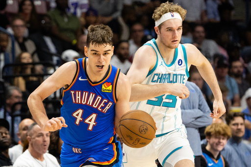 Oklahoma City Thunder guard Nikola Topic, left, drives the ball upcourt against Charlotte Hornets forward Liam McNeeley, right, during the second half of an NBA basketball preseason game in North Charleston, S.C., Sunday, Oct. 5, 2025. (AP Photo/Mic Smith)