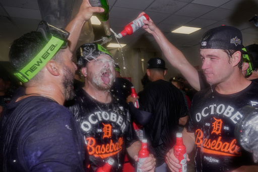 Detroit Tigers bullpen catcher Chris Chinea, left, catcher Jake Rogers, center, and catcher Dillon Dingler, right, celebrate in the locker room after defeating the Cleveland Guardians in Game 3 of an American League Wild Card baseball playoff series in Cleveland, Thursday, Oct. 2, 2025. (AP Photo/Sue Ogrocki)