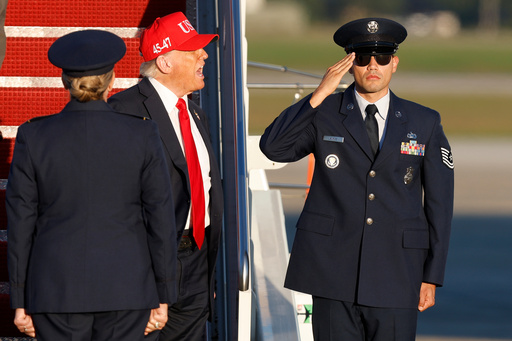 President Donald Trump, center, is greeted by Air Force 89th Air Wing Deputy Commander Melissa Dombrock, left, as he speaks to the media upon his arrival at Joint Base Andrews, Md., Sunday, Oct. 5, 2025, after returning from Norfolk, Va. (AP Photo/Luis M. Alvarez)