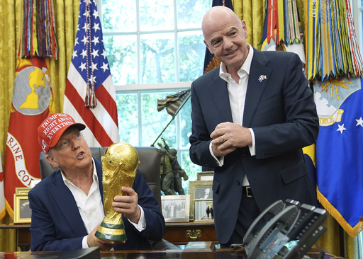 FILE - President Donald Trump holds the FIFA World Cup Winners Trophy as FIFA President Gianni Infantino looks on during an announcement in the Oval Office of the White House, Aug. 22, 2025, in Washington. (AP Photo/Jacquelyn Martin, File)