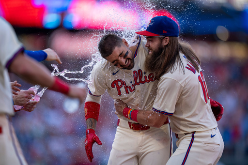 Philadelphia Phillies' Nick Castellanos, left, celebrates with Brandon Marsh, right, and other teammates after driving in the winning run during the 10th inning of a baseball game against the Minnesota Twins, Sunday, Sept. 28, 2025, in Philadelphia. (AP Photo/Chris Szagola)