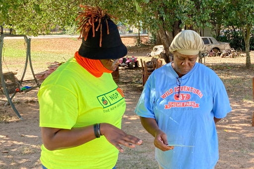FILE - Erika Hardwick, left, a paid canvasser with the New Georgia Project Action Fund, shares literature with Patricia Lee and urges her to vote, Oct. 5, 2022, in Dawson, Ga. (AP Photo/Jeff Amy, File)