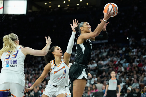 Las Vegas Aces center A'ja Wilson (22) shoots as Phoenix Mercury guard Sami Whitcomb (33) and forward Satou Sabally (0) defend during the second half in Game 2 of the WNBA basketball finals, Sunday, Oct. 5, 2025, in Las Vegas. (AP Photo/John Locher)