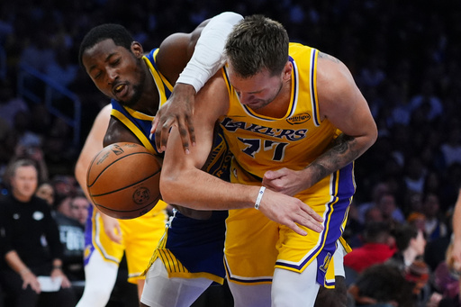 Golden State Warriors guard Jonathan Kuminga, left, works for a round against Los Angeles Lakers' Luka Dončić (77) during the first half of an NBA basketball game Tuesday, Oct. 21, 2025, in Los Angeles. (AP Photo/Ethan Swope)