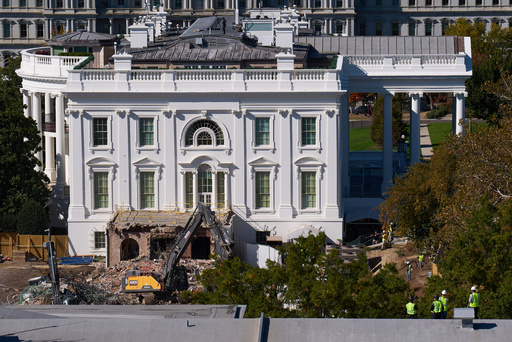 Construction workers atop the U.S. Treasury, bottom right, watch as work continues on a largely demolished part of the East Wing of the White House, Thursday, Oct. 23, 2025, in Washington, before construction of a new ballroom. (AP Photo/Jacquelyn Martin)