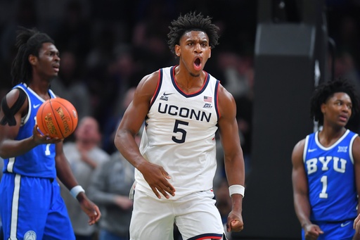 UConn forward Tarris Reed Jr., center, celebrates in front of BYU forward Khadim Mboup, left, and guard Robert Wright III after scoring in the first half of an NCAA college basketball game, Saturday, Nov. 15, 2025, in Boston. (AP Photo/Steven Senne)