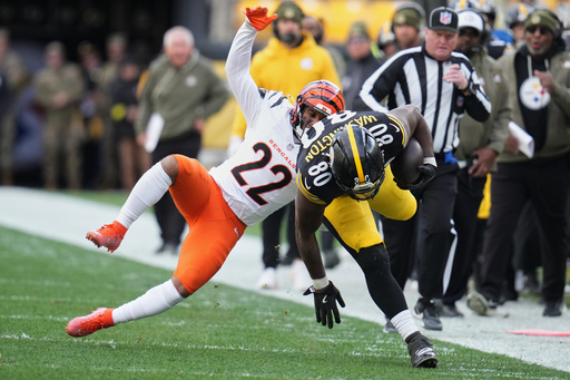 Pittsburgh Steelers tight end Darnell Washington (80) avoids a tackle by Cincinnati Bengals safety Geno Stone (22) during the first half of an NFL football game Sunday, Nov. 16, 2025, in Pittsburgh. (AP Photo/Gene J. Puskar)