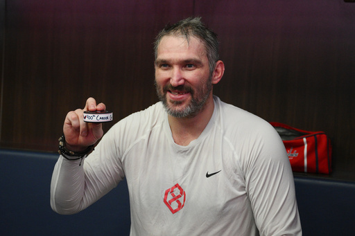 Washington Capitals left wing Alex Ovechkin poses in the locker room with his 900th NHL career goal puck in an NHL hockey game against St. Louis Blues, Wednesday, Nov. 5, 2025, in Washington. (AP Photo/Nick Wass)