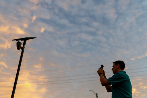Alek Schott photographs a Flock Safety license plate reader in his neighborhood, Thursday, Oct. 16, 2025, in Houston. (AP Photo/David Goldman)