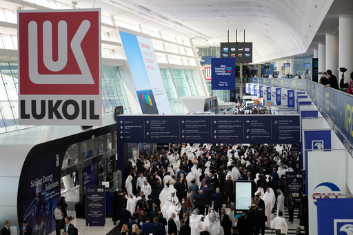 Logo of Russian oil company Lukoil hangs from the ceiling as visitors and delegates leave the hall after the inaugural session of annual Abu Dhabi International Petroleum Exhibition & Conference (ADIPEC) in Abu Dhabi, United Arab Emirates, Monday, Nov. 3, 2025. (AP Photo/Altaf Qadri)