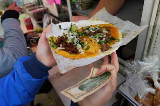 A bicyclist receives food from a street vendor Yulisa Robles, right, at Gage Park during Street Vendor Bike Tour Series, in Chicago, Sunday, Nov. 2, 2025. (AP Photo/Nam Y. Huh)