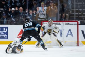 Vegas Golden Knights goalkeeper Carl Lindbom, right, prepares to defend a shot on goal as Utah Mammoth center Logan Cooley, center, takes the puck downice during the third period of an NHL hockey game, Monday, Nov. 24, 2025, in Salt Lake City. (AP Photo/Anna Fuder)