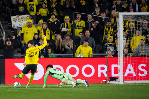 Columbus Crew forward Max Arfsten (27) kicks the ball as FC Cincinnati goalkeeper Roman Celentano (18) tries to defend during the first half of Game 2 in the first round of MLS soccer's Eastern Conference playoffs, Sunday, Nov. 2, 2025, in Columbus. (AP Photo/Tanner Pearson)