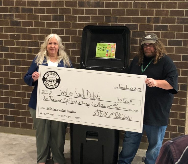 Public Works Administration Operations Manager Shannon Truax, left, and AFSCME President Sean Jewett display a large check showing the total amount of money donations contributed during the ‘Pack the Pantry’ food drivel; also…