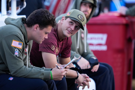 Injured San Francisco 49ers quarterback Brock Purdy, middle, sits on the bench during the first half of an NFL football game against the Los Angeles Rams in Santa Clara, Calif., Sunday, Nov. 9, 2025. (AP Photo/Godofredo A. Vásquez)