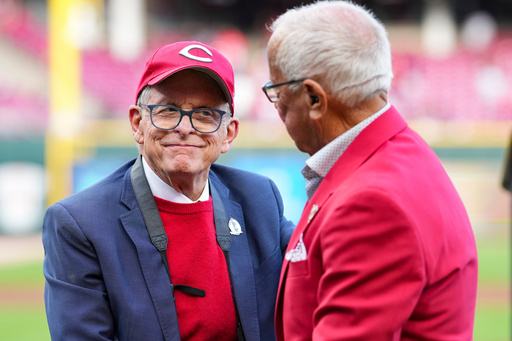 FILE - Hall of Fame broadcaster Marty Brennaman, right, speaks with Ohio Gov. Mike DeWine, left, during "Marty Brennaman Day" prior to a baseball game between the New York Mets and the Cincinnati Reds, Saturday, Sept. 6, 2025, in Cincinnati. (AP Photo/Jeff Dean, File)
