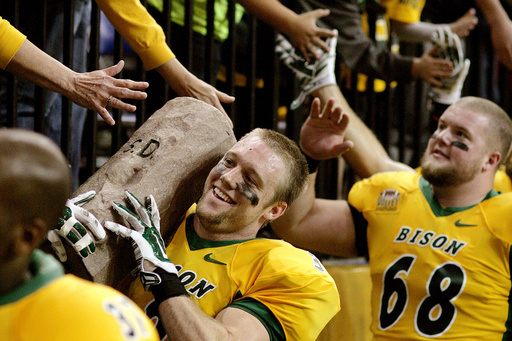 FILE - North Dakota State receiver Trevor Gebhartcarries the Dakota Marker off the field, trailed by teammate Zac Johnson, right, following the team's 37-17 victory over South Dakota State in an NCAA college football game Saturday, Nov. 1, 2014, in Fargo, N.D. (AP Photo/Bruce Crummy, File)